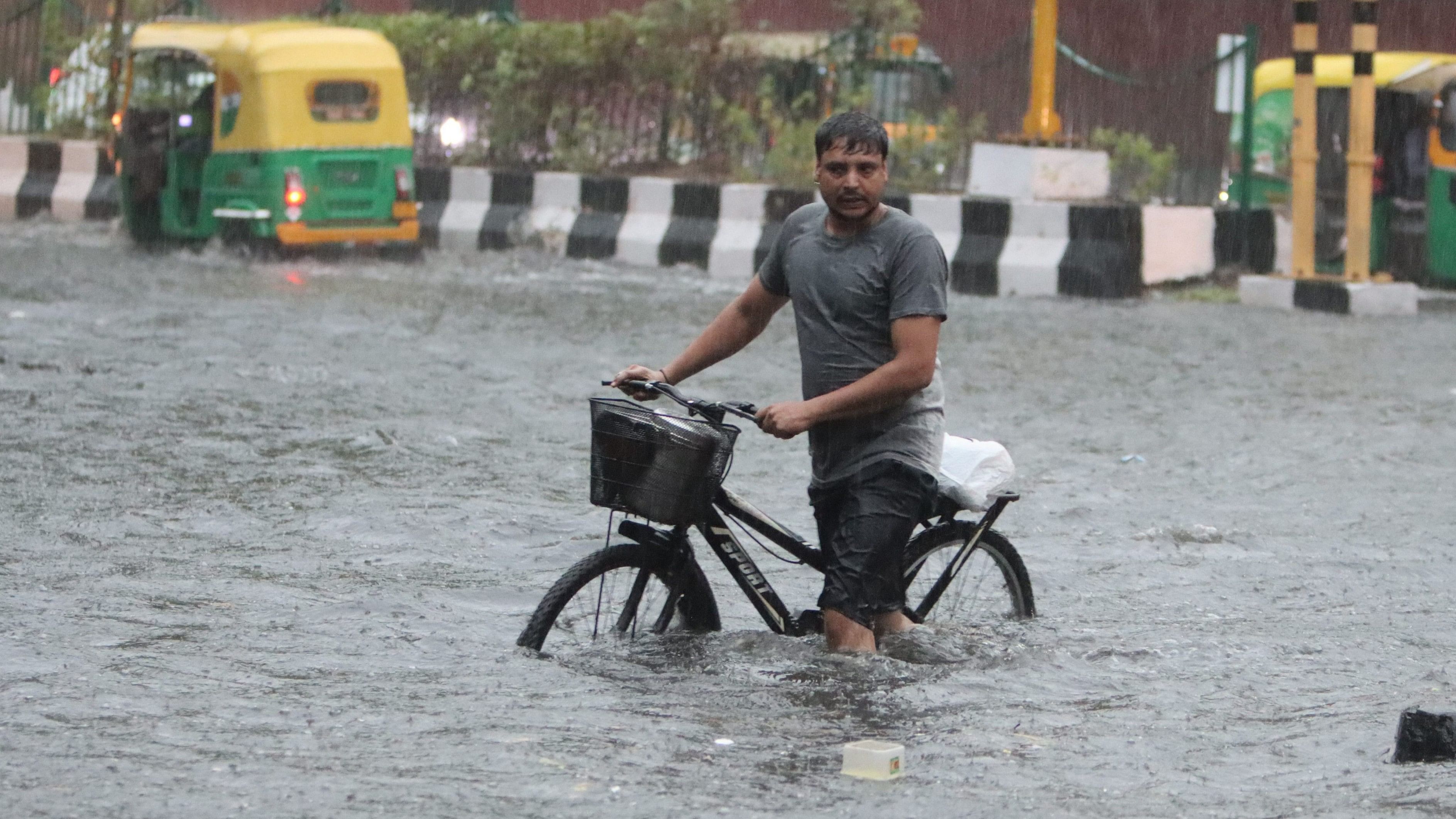 People wade through a waterlogged road amid rains, in New Delhi, Friday morning, June 28, 2024.