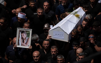 Men carry the white coffins of the children, and a photograph of one victim